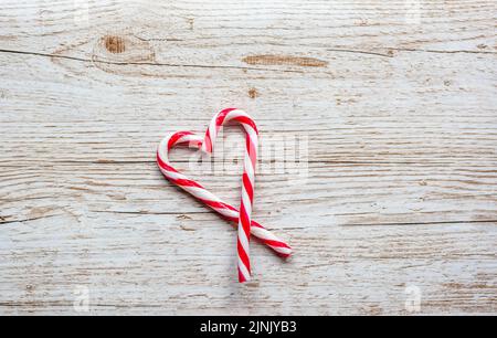 Candy cane christmas sweet red and white striped food in shape of heart. Placed on wooden desk. Winter and christmas theme. Stock Photo