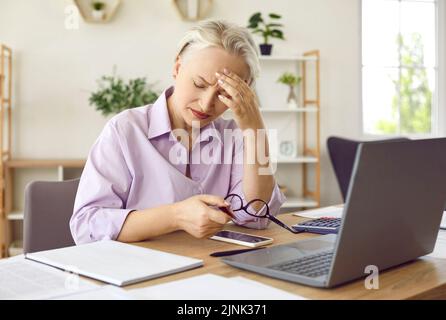 Mature woman feeling tired and suffering from a headache after working on her laptop Stock Photo