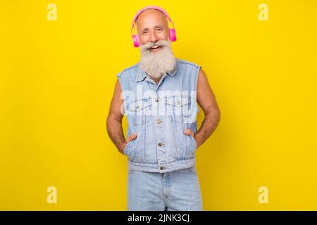 Photo of charming adorable retired guy wear jeans waistcoat listening songs earphones isolated yellow color background Stock Photo