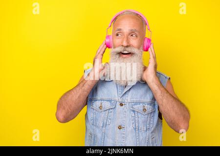 Photo of dreamy funny man pensioner dressed denim vest enjoying music looking empty space isolated yellow color background Stock Photo