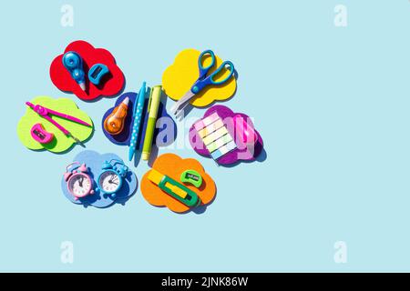Back to school concept. Different stationery on the rainbow color clouds on light blue background. Flat lay, copy space. Stock Photo