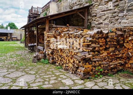 Firewood cut and stacked on the street in a medieval looking street. Estonia. Stock Photo