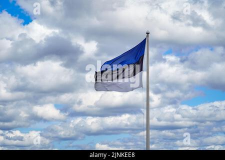 Flag of Estonia on the background of the blue sky and white clouds. Stock Photo