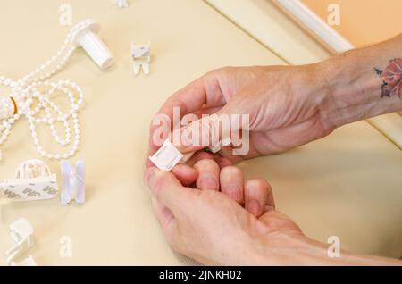 Assembly of roller blinds. Male hands are assembling roller blinds, close-up. Stock Photo