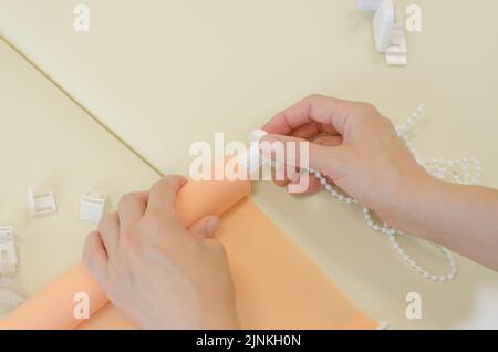 Assembly of roller blinds. Women's hands are assembling roller blinds, close-up. Stock Photo