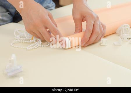 Assembly of roller blinds. Women's hands are assembling roller blinds, close-up. Stock Photo