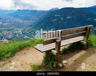 a bench overlooking the alpine valley of the city Merano surrounded by the Texel group mountains (Oetztaler Alpen in Südtirol, South Tyrol, Italy) Stock Photo