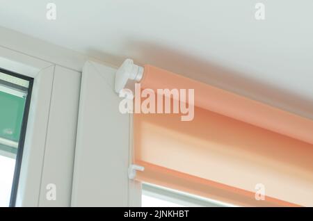 Roller blinds on the window. Fastening roller blinds to the window frame with double-sided tape Stock Photo