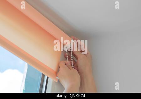 Installation of roller blinds. Close-up of female hands installing roller blinds on the window Stock Photo