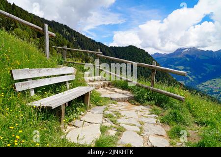 a bench overlooking the alpine valley of the city Merano surrounded by the Texel group mountains (Oetztaler Alpen in Südtirol, South Tyrol, Italy) Stock Photo