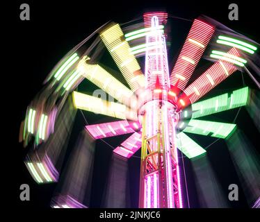 Multicolored Star Flyer tall Carousel rotating on long chains in an amusement park. Entertainment and leisure activities concept. Stock Photo