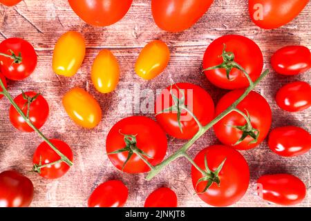 Flat lay view of a mixture of ripe tomatoes on a wooden table top Stock Photo