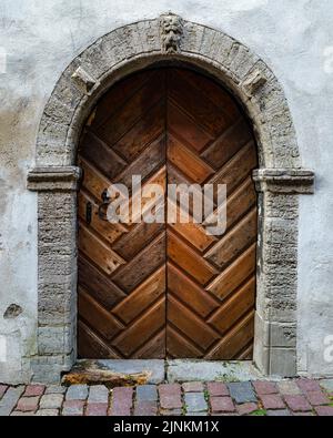 Old wooden door with stone arch in medieval building. Stock Photo