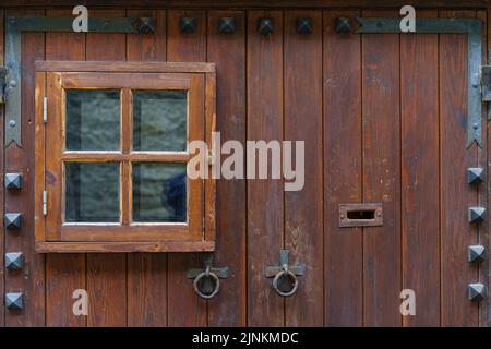 Detail of medieval wooden door with small window and metal fittings. Stock Photo