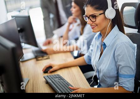 Friendly young woman helpline operator with headphones in call center Stock Photo