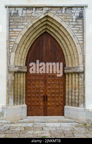 Ancient wooden door in a stone arch with also stone facade. Stock Photo
