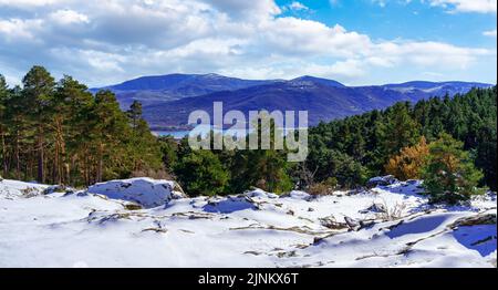 Panoramic mountain landscape with freshly fallen snow in the valley and lake in the background. Guadarrama, Madrid. Stock Photo