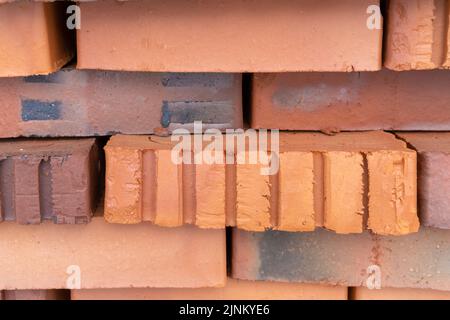 A stack of red bricks. Insulated building bricks. Red clay bricks are stacked on wooden pallets. Production of bricks from clay. Stock Photo