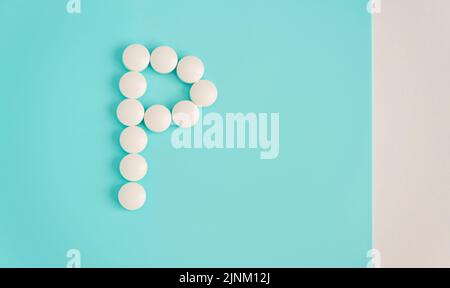 Letter P made from white pills on a blue background. White medical pills. Macro top view with copy space. Health care and pills concept, pharmaceutica Stock Photo