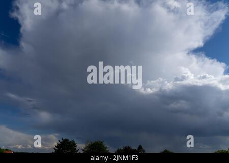 Thunderstorm clouds towering in a bright blue summer sky Stock Photo