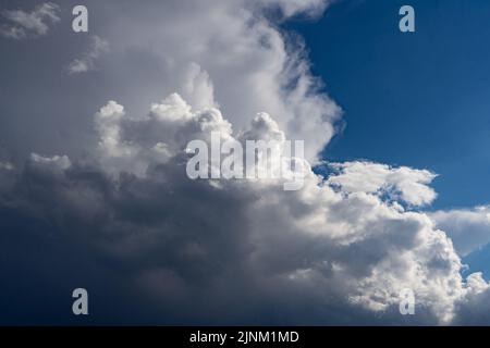 Thunderstorm clouds towering in a bright blue summer sky Stock Photo