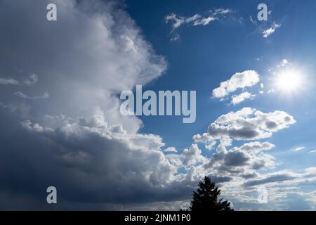 Thunderstorm clouds towering in a bright blue summer sky Stock Photo
