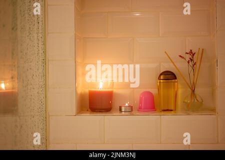 Shower cubicle with water drops on glass. Flames of burning candles. Spa, relax. Stock Photo
