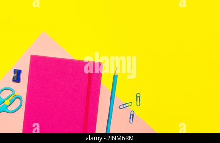 School pink notebook and various stationery on yellow background. Back to school concept. Flat lay, top view, copy space. Stock Photo