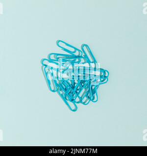Paper clips isolated on blue background. Monochromatic composition. School or business concept. Flat lay, top view. Stock Photo