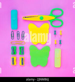 Neatly arranged pattern made of wooden pencils on pink background with school supplies. Creative flat lay, top view. Back to school concept. Stock Photo