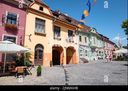 Old town square with light colored ancient buildings in the medieval center of Sighișoara in Transylvania, Romania. Stock Photo