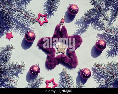 Christmas backdrop with fluffy fur star Xmas wreath and red bubble toys with polka dots. Toned image, green burgundy flat lay. Stock Photo