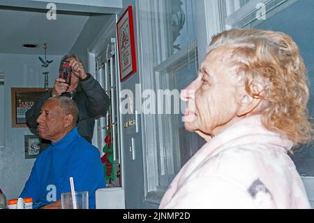 Female Senior citizen sitting at dining table next to black man. Stock Photo