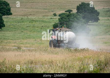 Red Case Puma 340 tractor towing a 30,000 litre water trailer on a dirt stone track Stock Photo