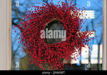 Wreath of red berries on the window glass with reflections Stock Photo