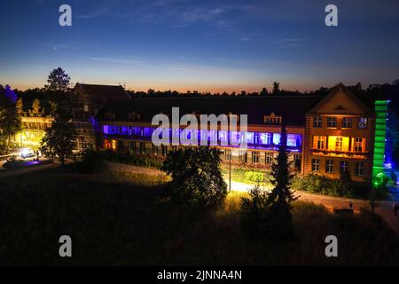Germany. 12th Aug, 2022. 12 August 2022, Brandenburg, Beelitz-Heilstätten: The illuminated surgery building at the 'Long Nights at the Treetop Trail' event in Beelitz-Heilstätten. Various artists and musicians play for visitors in the fabulously illuminated park. Photo: Gerald Matzka/dpa/ZB Credit: dpa picture alliance/Alamy Live News Stock Photo