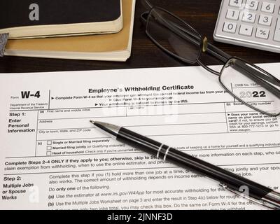 An IRS W-4 Employees Withholding Certificate form, issued in 2022, is shown on display up close. Stock Photo