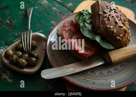Sunflower seed roll with tomatoes and olives on wooden board Stock Photo
