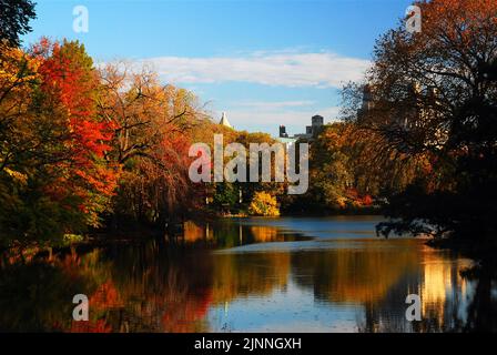The autumn colors and fall foliage are reflected in the calm waters of the lake in New York's Central park on a crisp sunny day Stock Photo