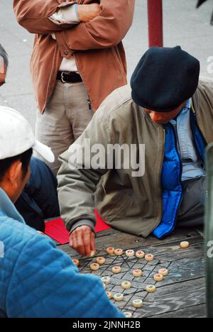 A group of senior Asian friends play xiangqi, a traditional Chinese game similar to chess, in a park in the Chinatown neighborhood of San Francisco Stock Photo