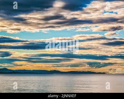 Threatening storm clouds over calm water and coastline Stock Photo