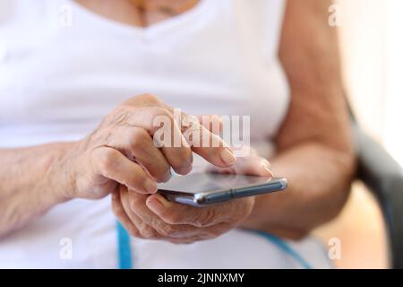 Old grandmother holding modern cellphone in hands. Woman using smartphone Stock Photo