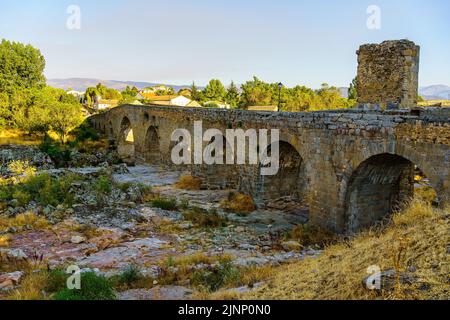 Medieval stone bridge that crosses the dry river in a summer season with great drought and lack of rain, Puente Congosto, Spain. Stock Photo