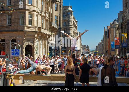 Edinburgh, Scotland, August 11, 2022 Festival Fringe in the Royal Mile acrobats performing on a bar and from the hands supported by an aid Stock Photo