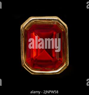 polygonal red ruby gem on golden ring, black background Stock Photo