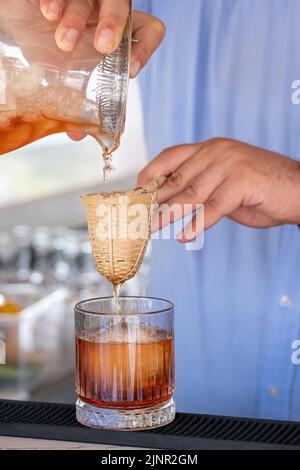 Professional bartender pouring cocktail into glass glass with shaker Stock Photo