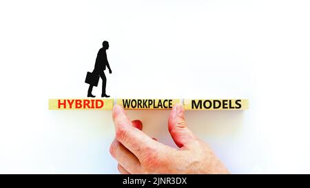 Hybrid workplace models symbol. Concept words Hybrid workplace models on wooden blocks. Businessman hand. Beautiful white background. Business hybrid Stock Photo