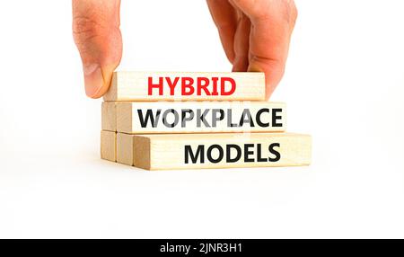 Hybrid workplace models symbol. Concept words Hybrid workplace models on wooden blocks. Businessman hand. Beautiful white background. Business hybrid Stock Photo