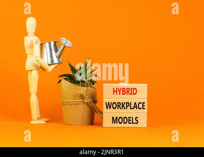 Hybrid workplace models symbol. Concept words Hybrid workplace models on wooden blocks. Businessman model. Beautiful orange background. Business hybri Stock Photo