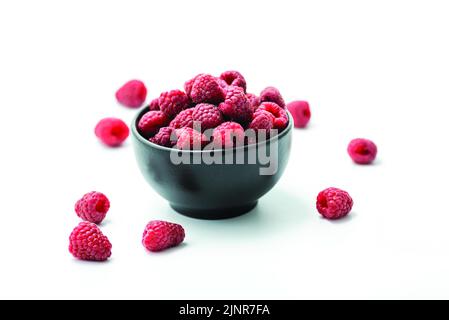 Ripe sweet raspberries in bowl on white background Stock Photo